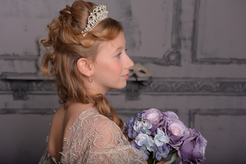 a girl in a smart white dress with a diadem in her hair and a bouquet of flowers in her hands
