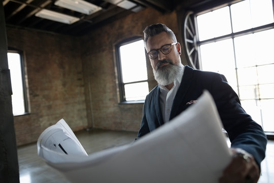Male architect reviewing blueprints in new industrial office