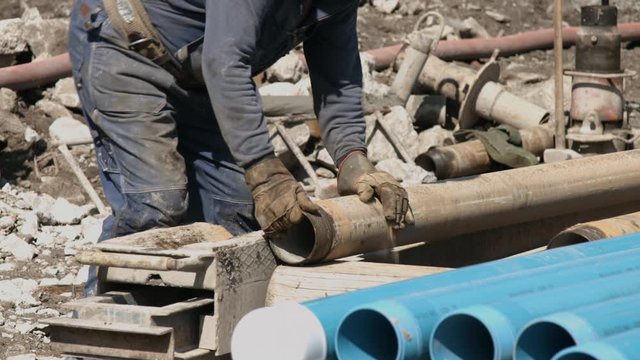 Worker preparing drill pipe for connecting to the borehole drilling rig