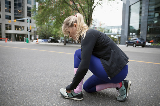 Female runner tying shoelace on urban street