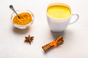 Glass cup of traditional indian masala chai tea with ingredients above. Cinnamon, cardamom, anise over white texture background