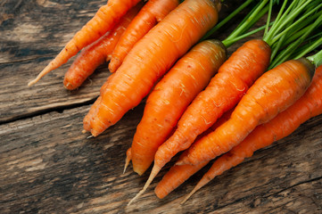Bunch of fresh organic carrots on a wooden rustic table.