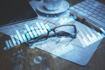 Financial chart hologram with glasses on the table background. Concept of business. Double exposure.