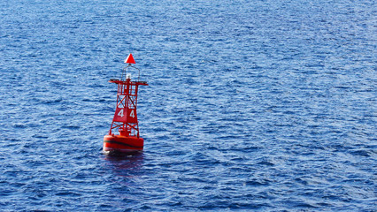 Red coastal buoy in blue ocean water. safety and navigation of ships near the shore