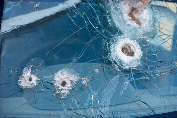 Bullet hole on a car windshield. Car window after a raid has a bullet hole. Broken glass. Bullet holes in a front windshield. Broken Windshield.
