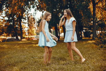 Beautiful girls on a blue dresses. Friends have fun in a summer park