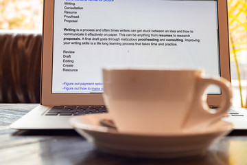 A cup of coffee against a laptop screen. Writing a journal concept