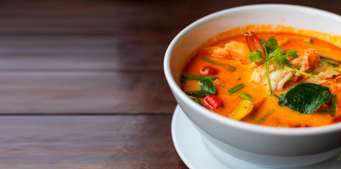 Tom Yam kung Spicy Thai soup with shrimp in white bowl on wood table. With copy space for text or design.