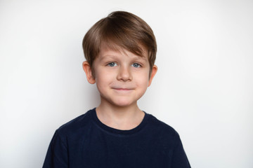 Photo of cute young happy boy in dark t shirt looking at camera