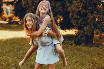 Beautiful girls with a colorful dry paints. Friends have fun in a summer park