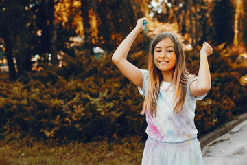 Beautiful girl with a colorful dry paints. Little lady have fun in a summer park