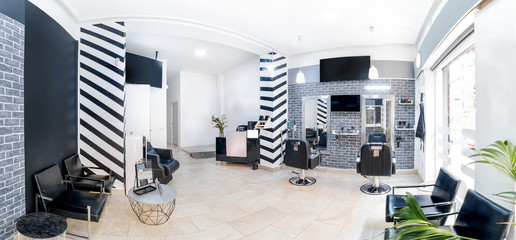 Fototapeta na wymiar Reception in a beauty salon with desk,plant and banners. Panorama of a hair salon modern bright beauty salon interiorBlack and white decoration with mirrors, chairs,tv screen and mockup banners.