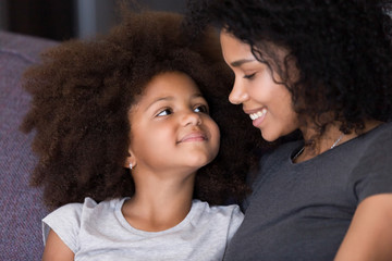 Close up of black mom and daughter hugging at home