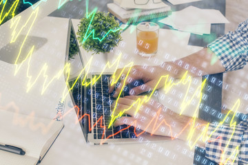 Multi exposure of graph with man typing on computer in office on background. Concept of hard work. Closeup.