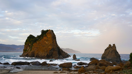 volcanic mountainous islands in the blue water of the Pacific Ocean. tropical islands of Japan overgrown with green plants against a beautiful sunset sky. Aburatsu