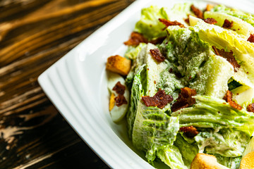 Healthy Caesar salad made of fresh vegetables on wood table