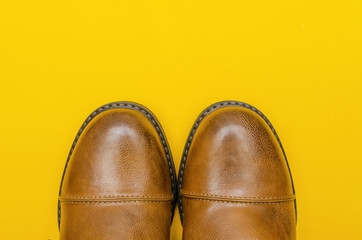Rounded nose of men's brown shoes on a yellow background close-up with a copy of the space