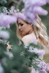 Fototapeta premium young beautiful bride with a wedding bouquet near lilac bushes