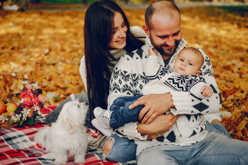 Family in a autumn park. Woman in a white sweater. Cute newborn little boy with parents
