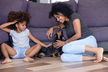 Happy black mom and daughter relax having fun with dog - Powered by Adobe