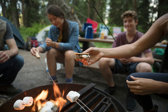 Teenage Outdoor School Students Toasting Marshmallows, Making Smores At Campsite Campfire