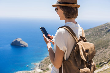 Young tourist woman using smart phone over beautiful landscape with sea at background. Travel,...