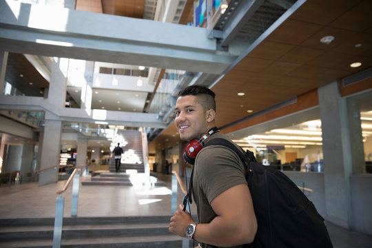 Portrait Smiling, Confident Male College Student With Backpack And Headphones In Lobby