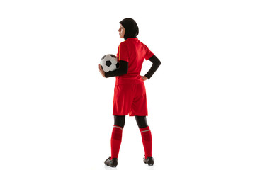 Arabian female soccer or football player isolated on white studio background. Young woman holding the ball, training, practicing in motion and action. Concept of sport, hobby, healthy lifestyle.