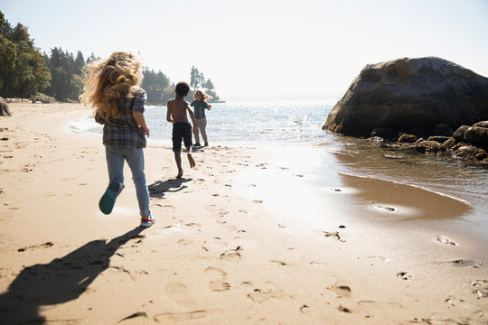 Boy and girl friends running on sunny ocean beach