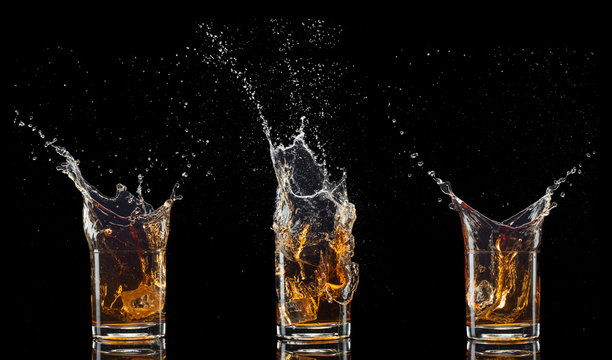 Glass Of Whiskey With Splash Isolated On Black Background