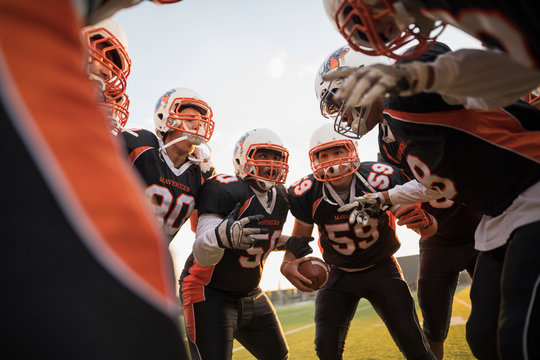 Teenage boy high school football team talking in huddle on football field