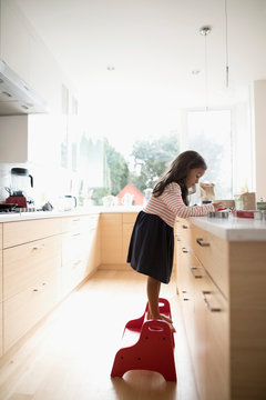 Girl On Step Stool Decorating Cookies At Kitchen Counter