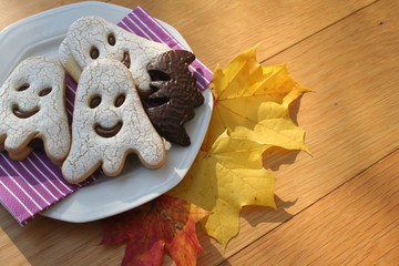 Halloween cookies in shape of a ghost  and bat filled with choocolate on wooden table. Halloween background