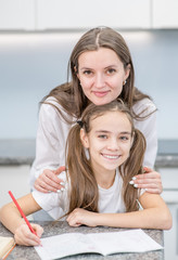 Portrait of happy mother and daughter doing homework