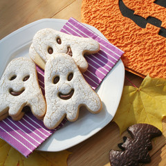 Halloween cookies in shape of a ghost  and bat filled with choocolate on wooden table. Halloween background