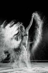 Obraz premium Beautiful girl model on a black background throws flour