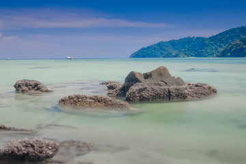 Obraz premium view of arch rocks on smooth silky blue-green sea with blue sky background. (Long Exposure Technic) Khao Chong Kad, Surin island, southern of Thailand.