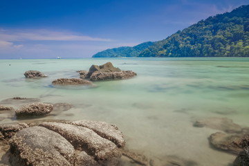 view of arch rocks on smooth silky blue-green sea with blue sky background. (Long Exposure Technic)...