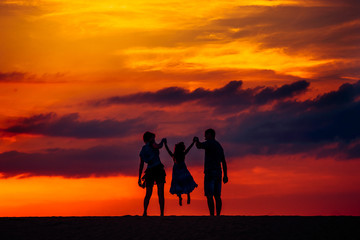 Happy family on meadow at summer sunset