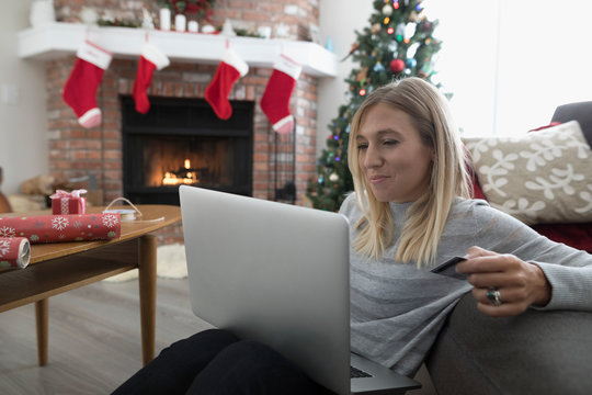 Woman with credit card online Christmas shopping at laptop in living room