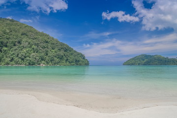 Fototapeta na wymiar view seaside of white sand beach with blue-green sea with green forest and blue sky background, Surin island, Mu Ko Surin National Park, Phang Nga, southern of Thailand.