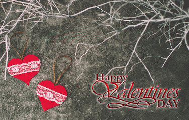 Holiday background for Valentine's Day on a gray cement background with white painted branches and a sheet of paper for text
