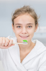Happy young girl holds toothbrush in bathroom at home