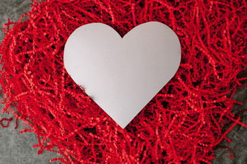 Holiday background for Valentine's Day on a gray cement background with red chopped wrapping paper and hearts.