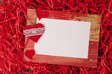 Holiday background for Valentine's Day on a gray cement background with red chopped wrapping paper and hearts.