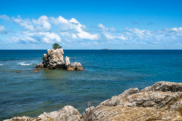 Sea stack and rocks on the coast at Rocher a la voile (Sailing Rock), historical landmark at Anse Vata Bay in Noumea, New Caledonia, French Polynesia, South Pacific Ocean.