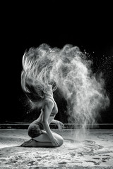 Obraz na płótnie Canvas Beautiful girl model on a black background throws flour