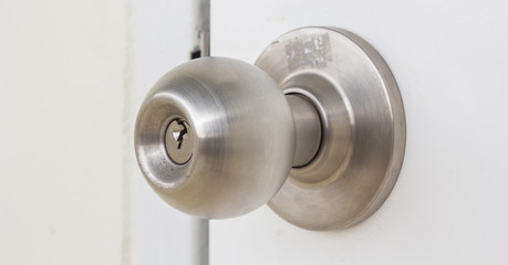 Aluminum door knob on the white door skin. - obrazy, fototapety, plakaty