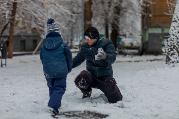 Fototapeta na wymiar A child and a man play snowballs. Dad, son, boy, childhood, winter.