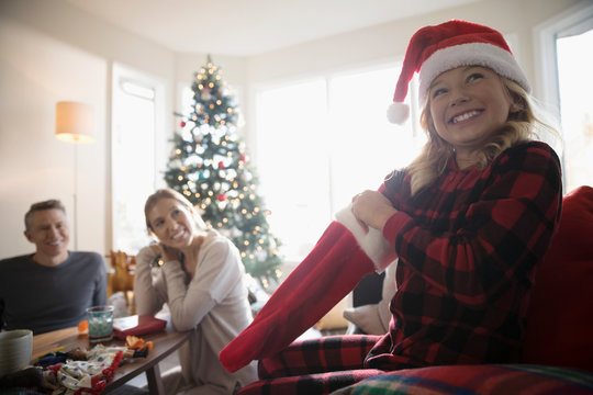 Parents watching happy daughter opening Christmas stocking in living room